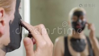 那个女人把泥面罩戴在脸上。 你的面部护理。 泥浆水疗程序。 日间水疗中心。 在人身上画一个黑色面具mov格式视频下载_正版视频编号1360883-摄图网