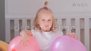 小可爱的金发女孩坐在她房间里的床上，带着粉红色的气球，微笑着。 肖像。mov格式视频下载_正版视频编号2110264-摄图网