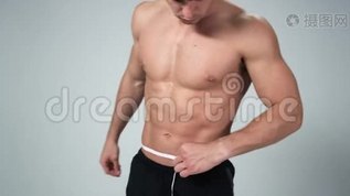 年轻漂亮的男人测量他完美的身体。 4kmp4格式视频下载_正版视频编号1663674-摄图网