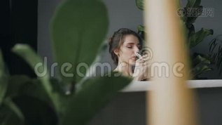 美丽的年轻女子在浴室里喝香槟，背景是绿色的花朵。美女喜欢mov格式视频下载_正版视频编号1814492-摄图网