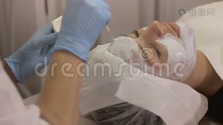 美容师用刷子把一个白色`面具戴在女孩的脸上mov格式视频下载_正版视频编号2041818-摄图网