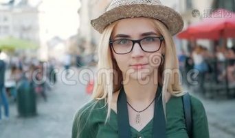 一个漂亮的金发女孩的肖像，戴着眼镜，戴着帽子，穿着蓝色牛仔裤夹克。视频下载-实拍视频-正版视频2270592-摄图网