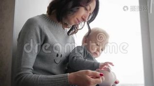 母亲和小儿子把硬币放进储蓄罐里，以备将来储蓄。mp4格式视频下载_正版视频编号1073094-摄图网