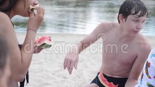 孩子们，青少年在海滩上休息，笑着吃西瓜，慢动作视频。 男孩和女孩的生活方式mp4格式视频下载_正版视频编号2134166-摄图网