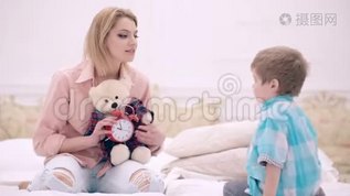年轻的妈妈带着可爱的小儿子和泰迪熊坐在家里的床上。 友好的家庭，一位年轻的母亲坐在旁边mov格式视频下载_正版视频编号297729-摄图网