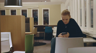 女人坐在桌子上玩手机视频素材