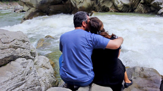 成年夫妇坐在河岸边拥抱视频素材