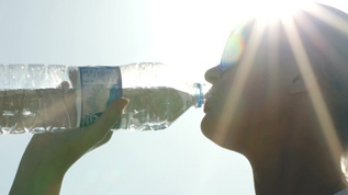 戴太阳镜的女人在阳光下喝水视频素材