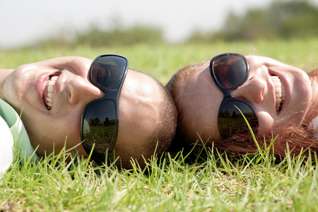 幸福的年轻夫妇在草坪上微笑