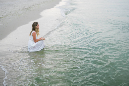 生活方式女人穿着白色连衣裙坐在海洋海岸