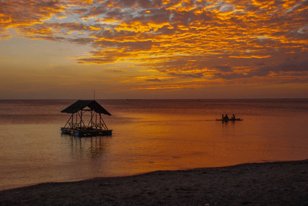 在海滩上美丽的夕阳。船和凉亭的剪影。香兰，班乃菲律宾