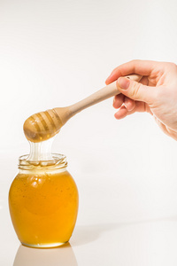 罐蜂蜜与孤立在白色背景上的木制 drizzler