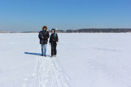 男人，女人和孩子在冬天走在雪河上