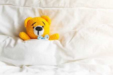 黄病泰迪熊躺在白色背景上的床上