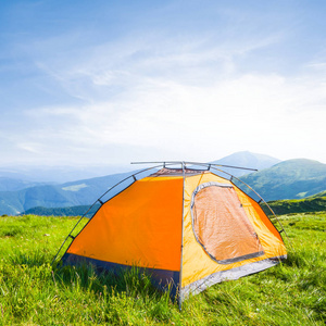 在清晨的绿色山间橙色旅游帐篷图片