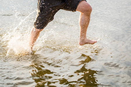 一个人沿着沙滩跑和溅水