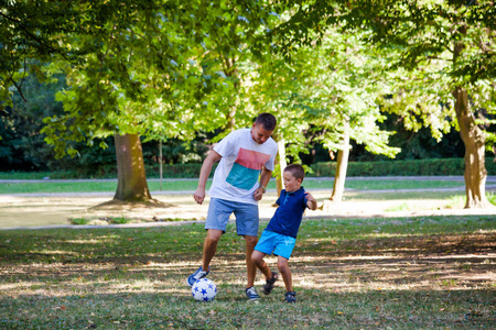 父亲和他的小儿子在踢足球公园