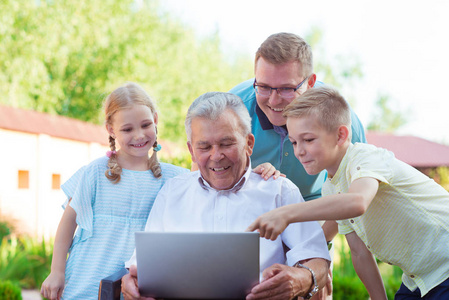 幸福的家庭和爷爷在互联网谈笔记本电脑