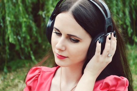 美丽的黑发女人大耳机听音乐与幸福的微笑