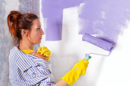 女人涂料白墙与紫色油漆滚筒