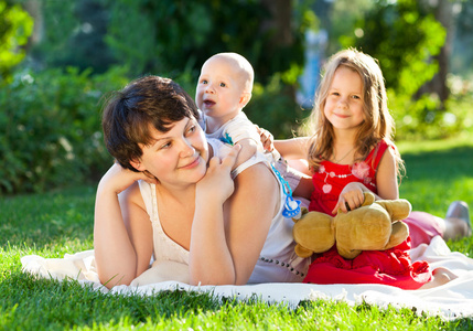 快乐妈妈和她的孩子一起在公园里玩。户外 por