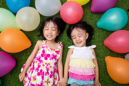 亚洲中国小姑娘躺在草中五颜六色的气球