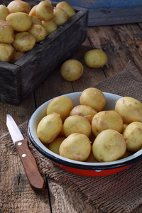 第一次收获的有机种植新土豆在碗上木制的背景。生的食物