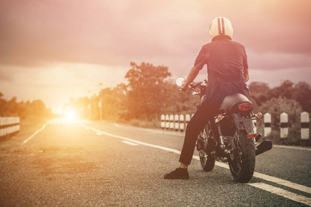 年轻男子驱动器与摩托车在街上，享有自由和积极的生活方式，骑自行车的人游玩乐