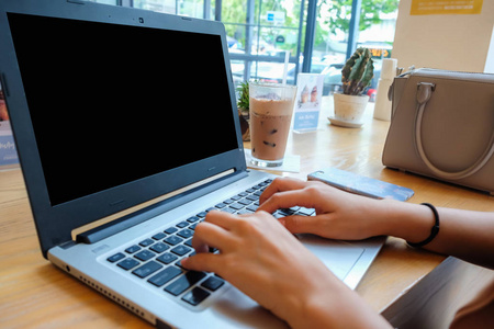 妇女手打字在咖啡馆关闭的膝上型计算机