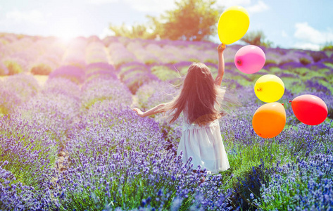 漂亮的孩子女孩跑与五颜六色的气球在薰衣草场夏天自由概念