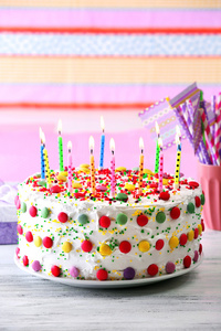 与彩色条纹背景上的蜡烛的生日蛋糕