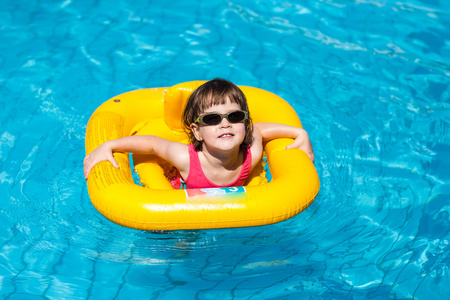 可爱的女孩游泳池游泳的在一个黄色的救生圈