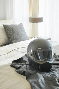 摩托车头盔和皮革夹克设置在现代卧室床上
