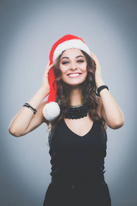 一个美丽的女人，穿上圣诞老人的帽子微笑的肖像