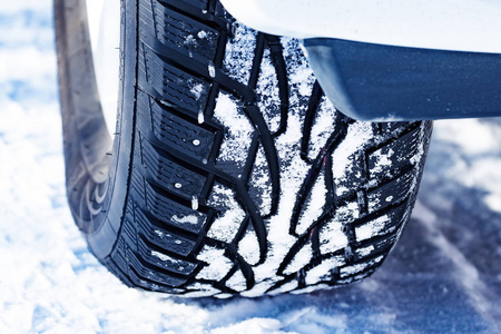 特写镜头的汽车镶嵌在冬天多雪道雪覆盖着的轮胎