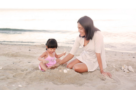 快乐充满爱的家庭。母亲和她的女儿孩子女孩玩沙滩上的沙子