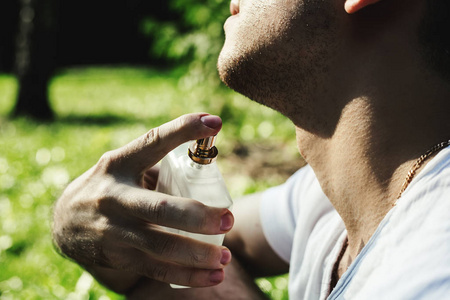 英俊的年轻男子在绿色背景上使用香水