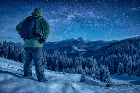 一名登山者在夜间站在雪坡上