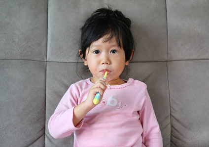 刷牙的沙发上粉红色的小女孩