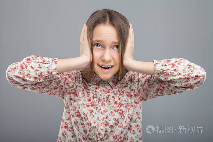 受惊吓的女孩将关闭用双手捂住耳朵