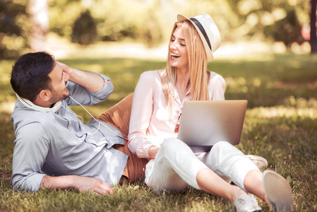 幸福的情侣，在公园里使用便携式计算机
