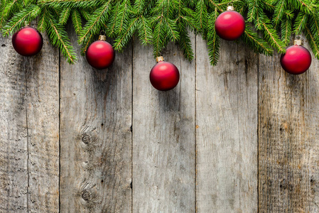 冷杉圣诞树装饰木制背景上。红色的装饰物挂在树枝上旧木板