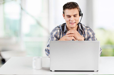 快乐的年轻人在他的笔记本电脑上工作