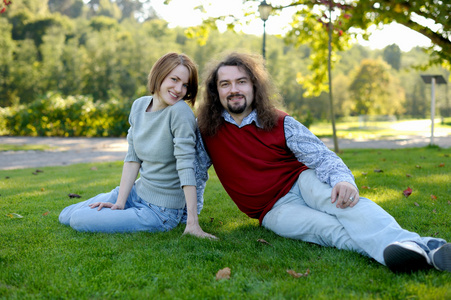 一对年轻夫妇坐在公园的草地上