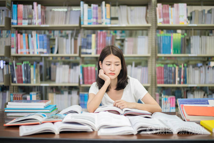 亚洲女学生无聊在与大量的图书馆看书