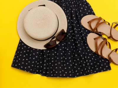 时尚的概念。女性夏季衣橱。戴着草帽 裙 太阳镜 凉鞋。黄色背景