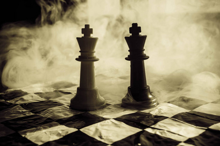 国际象棋棋盘游戏概念经营思路和竞争与战略思想概念。国际象棋棋子上与烟和雾的深色背景和窗口与阳光