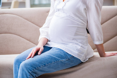 孕妇的肚子肚子坐在家里的沙发上