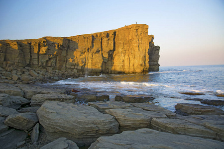 力量的磐石，折叠在蓝色的大海，与太阳眩光，雄伟壮观的岩石