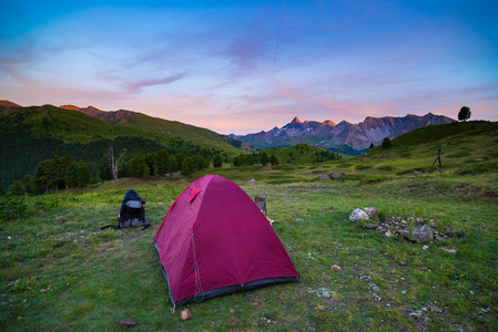 带上阿尔卑斯山海拔高帐篷露营。白雪皑皑的山脉和日落风景色彩斑斓的天空。冒险和探索在夏天